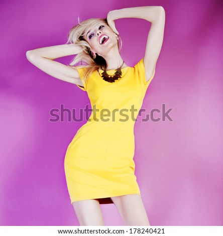 Smiling beautiful blonde young woman dancing wearing fashionable dress. Summer happy time.