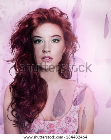 Artistic portrait of beautiful brunette woman with long curly hair posing over flying feathers. Studio shot.