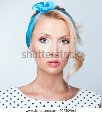 Portrait of retro beautiful blonde woman. Girl looking at camera, wearing blue ribbon on hair