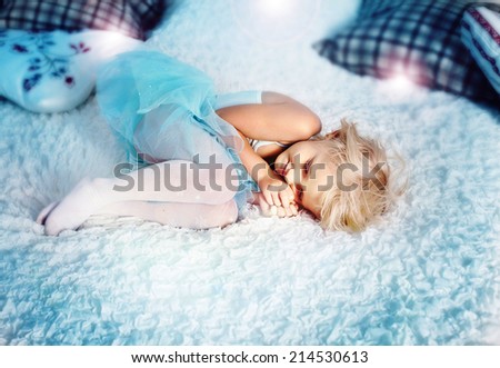 Cute little blonde girl sleeping in big bed, relaxing. Small girl wearing blue princess dress.