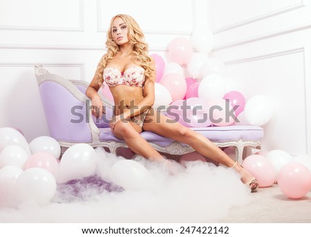 Sexy blonde perfect woman posing in lingerie over balloons, looking at camera. Girl with long hair.