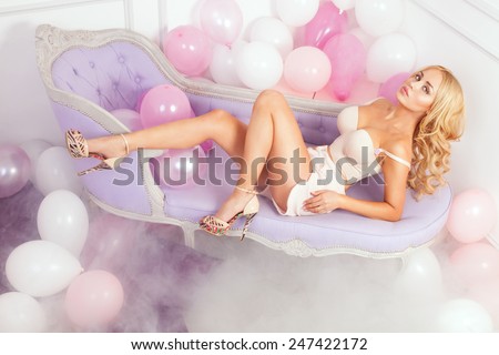 Sexy blonde perfect woman posing over balloons, looking at camera. Girl with long hair.