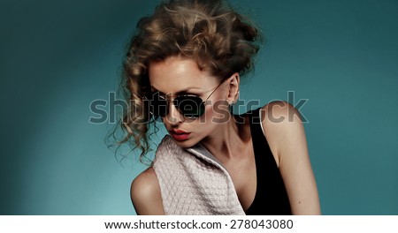 Closeup portrait of beautiful blonde woman wearing fashionable sunglasses. Blue background.