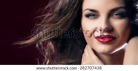 Beauty closeup portrait of attractive elegant brunette woman with red lips and long hair. Perfect makeup. Wind in hair.Girl with beautiful smile.
