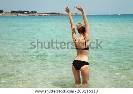 Young beautiful woman posing in water. Summer photo. Sunny day. Girl with slim body.