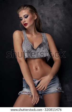 Sexy beautiful young woman posing in short jeans. Wet skin. Glamour makeup.