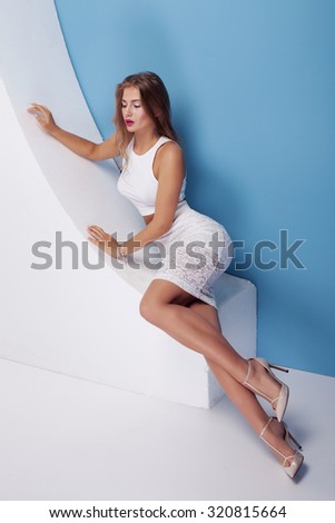Fashion photo of attractive sexy woman wearing white clothes. Studio shot. Blue background.