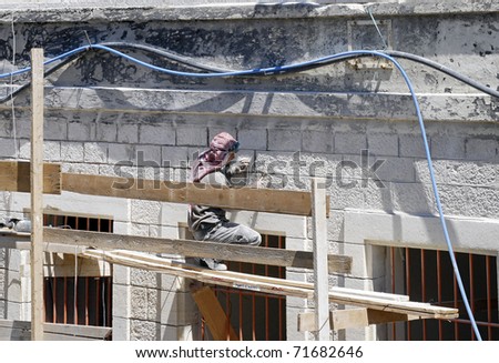 JERUSALEM- JUNE 12: Construction worker does masonry work on building in the Muslim Quarter of the Old City as seen from top of the Old City wall ramparts on June 12, 2007 in East Jerusalem.