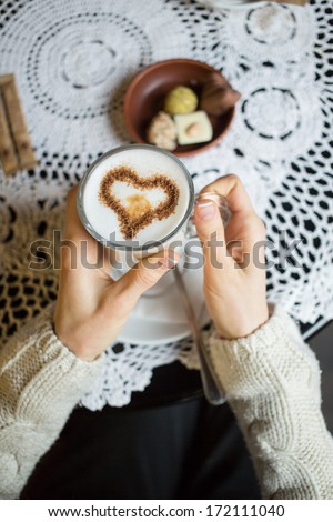 Coffee with heart symbol in woman\'s hands