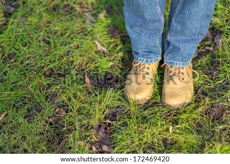 Close up view on woman\'s legs in blue jeans and boots walk through spring park