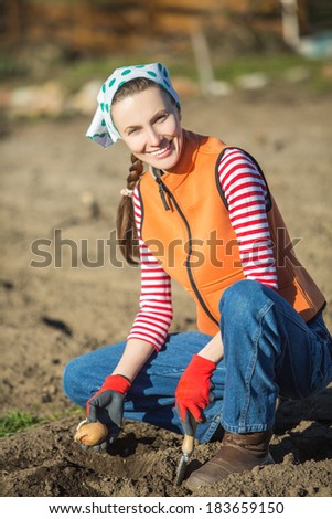 Woman gardener planting potato early in spring