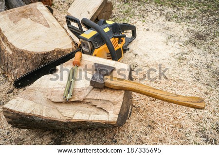 Wood tools - axe, chainsaw, chainsaw file on wooden log outdoor
