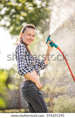 Summer garden, watering - beautiful girl watering lawn with garden hose in the garden. soft backlight