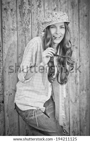 Sexy beautiful woman in hat and jeans over grunge wooden background. black and white grunge image