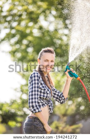 Beautiful young woman having fun in summer garden, woman working in the garden, watering plants