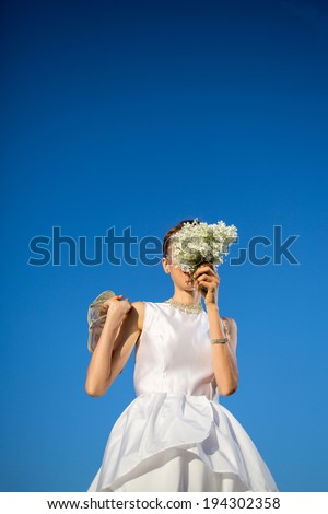 Portrait of beautiful bride with flowers over blue sky. focus on hands with flowers