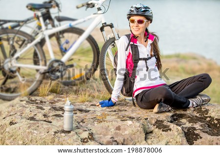 Sport bike woman sitting on a mountain next to bike relaxing and enjoying nature