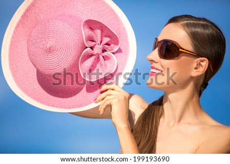 Funny summer woman with hat and sunglasses play with her hat on the beach. Enjoyment, summer fun concept