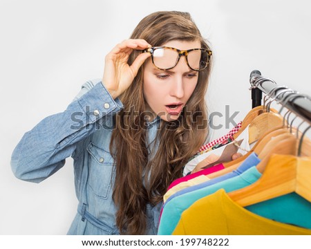 Shopping woman shocked over price tag. Funny shopper woman staring amazed at price over light grey background