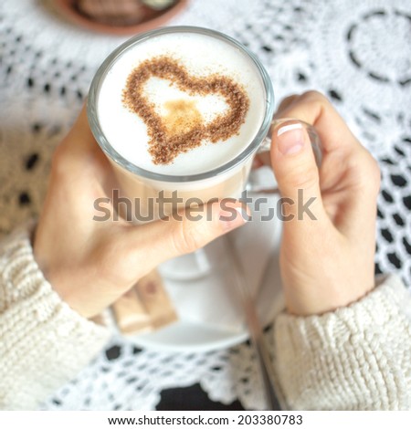 Woman holding hot cup of coffee with heart shape. focus on heart