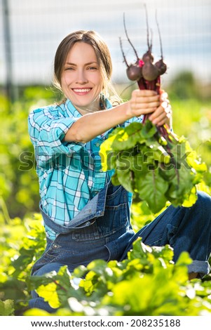 Garden work. Young woman with organic vegetables, bunch of beetroots in the garden. focus on face