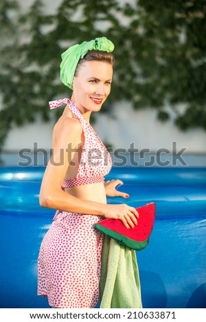 Beauty retro woman. Beautiful young girl in retro look in retro swimsuit near swimming pool going to swim