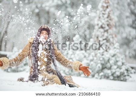Beautiful winter woman have fun in winter park, play with snow. focus on snow fall