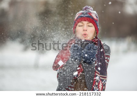 Christmas girl. Winter woman blowing snow on herself. Funny winter woman play with snow