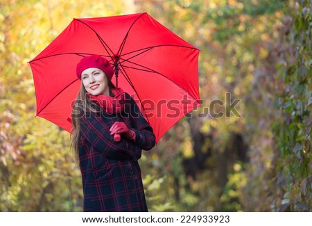 Beautiful woman portrait with red umbrella over yellow autumn background