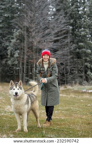 Woman and Alaskan Malamute walk in autumn forest. focus on woman