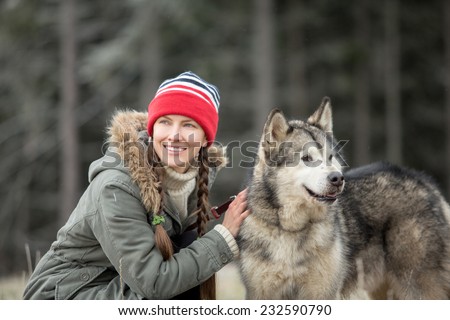 Woman and Alaskan Malamute walk in autumn dark forest. focus on dog, daylight