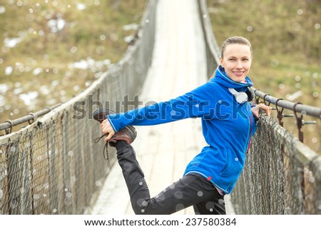 Winter running woman stretching before her workout. Fitness woman enjoying first snow. copy space