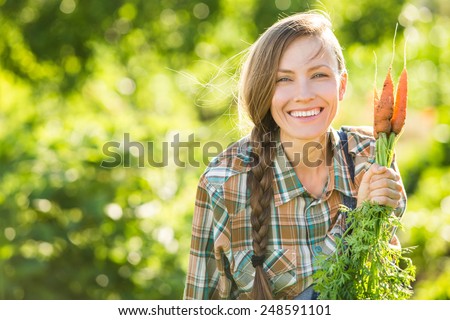 Gardening - Woman with organic carrots in a vegetable garden. backlight, copy space