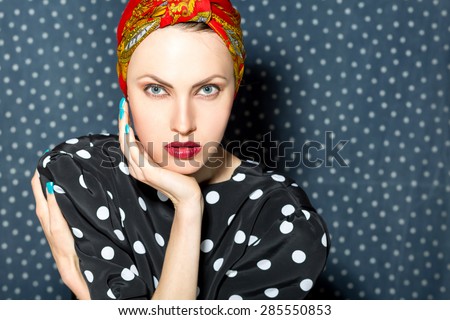 Fashion woman in head scarf and black polka dots dress over dark background