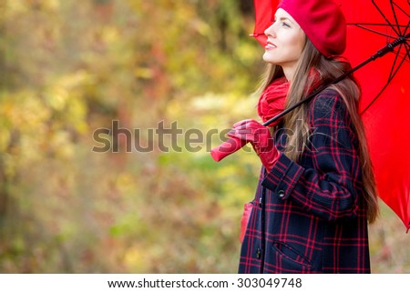 Autumn woman in autumn park with red umbrella, scarf and leather gloves