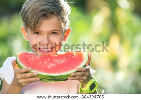 Funny kid eating watermelon outdoors in summer park. Child, baby, healthy food