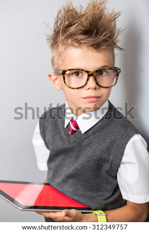 Fashionable little boy in sunglasses and funny hairstyle using tablet with empty screen. Stylish kid in suit. Fashion children. Business boy