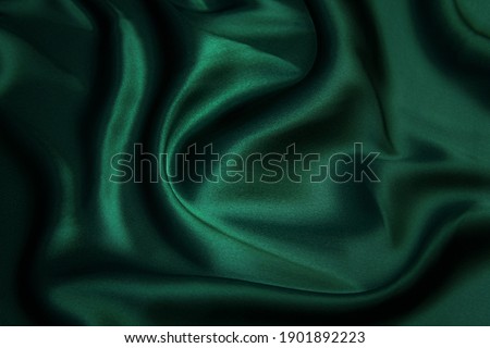 Texture, background, pattern. Texture of green silk fabric. Beautiful emerald green soft silk fabric.