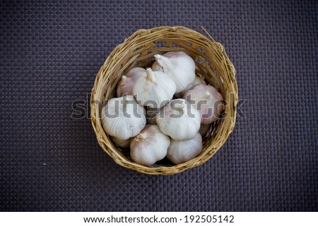 garlic in wicker basket on dark rattan plastic background