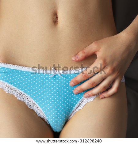 Slim female belly, blue panties a hand near the navel