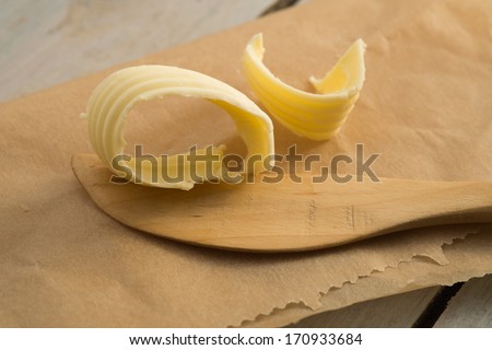 Butter curl and wooden butter knife on brown paper. close up