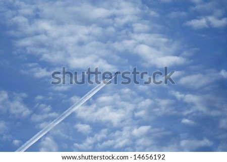 A high flying passenger jet leaves a contrail against a blue sky.