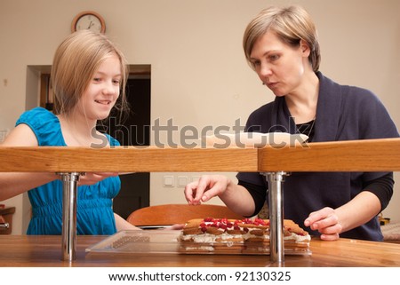 The mother teaches her daughter how to make cakes
