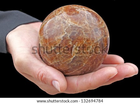 In a female hand there is a sphere which is made of a stone