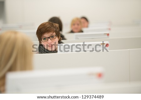 brunet girl works with desktop computer, other girls blurred work with computer too