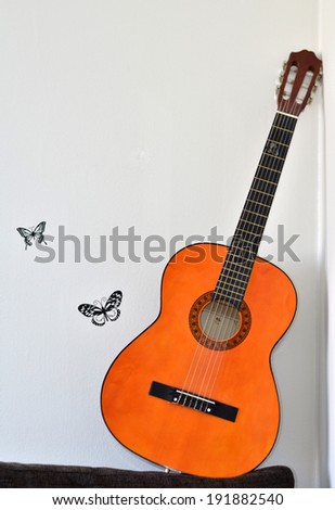 Guitar leaned against the wall with stickers butterflies