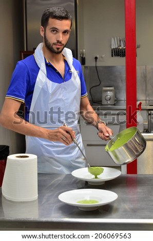 A handsome young man cooking in a white apron