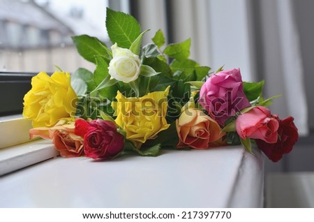 A bunch of multicolored roses on the windowsill