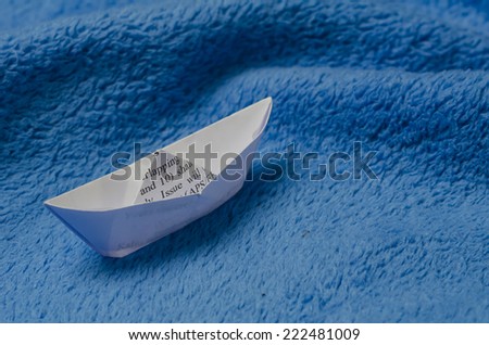 A paper boat on bright blue material