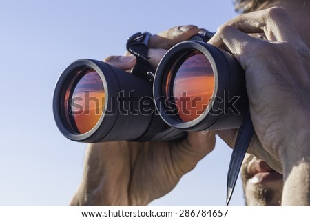 A man looking through the binoculars